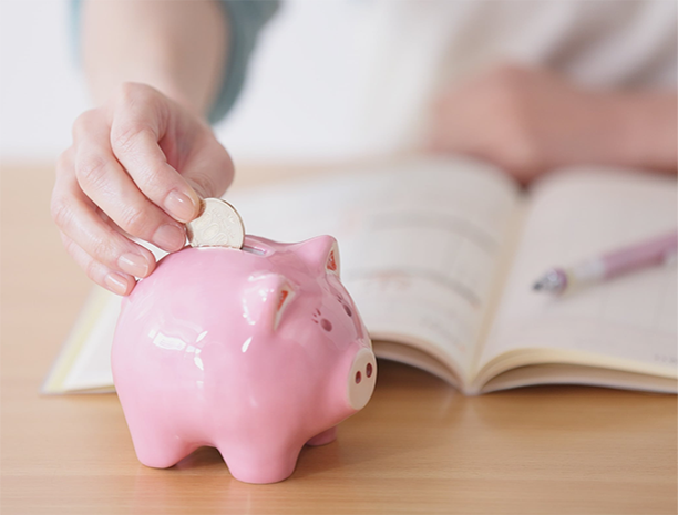 person with open book putting money in a piggy bank